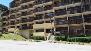 A multi-story hotel with balconies, a staircase, and a landscaped area.
