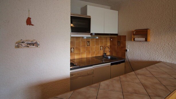 A compact kitchen with a stove, sink, and white cabinets. - 250m from ski slopes, 2nd floor, view mountain, balcony, tv, ski locker, 35m², Auris en Oisans (Auris)