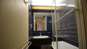 Une petite salle de bain avec un lavabo, un miroir et une baignoire.