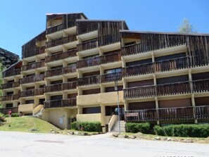 A multi-story hotel with balconies, a staircase, and a parking lot. - 250m from ski slopes, 2nd floor, view mountain, balcony, tv, ski locker, 35m², Auris en Oisans (Auris)