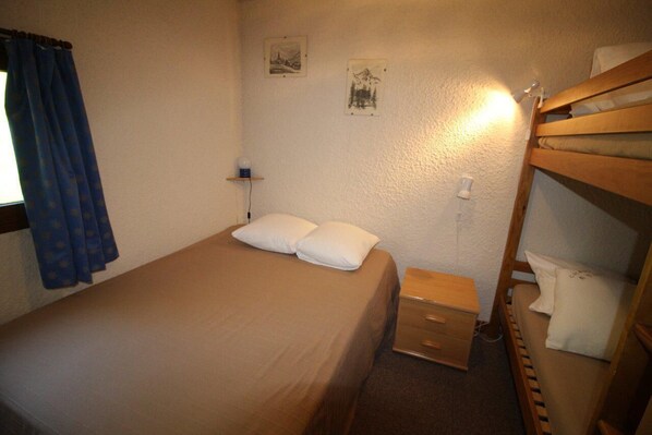 A single bed with two pillows, a bedside table with a lamp, and a bunk bed to the right. - 250m from ski slopes, 2nd floor, view mountain, balcony, tv, ski locker, 35m², Auris en Oisans (Auris)