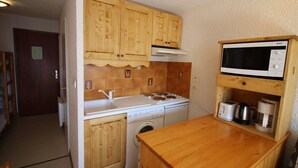 Une cuisine compacte dotée de meubles en bois, d’un four à micro-ondes, d’une cuisinière, d’un lave-linge et d’une machine à café.