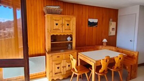 Une pièce aux murs en bois, une table à manger avec des chaises, un meuble avec des poignées en forme de cœur et une porte.