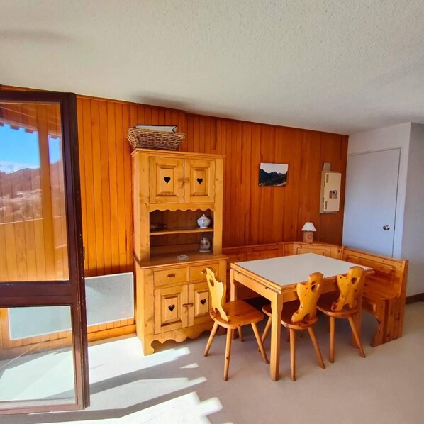 Une pièce aux murs en bois, une table à manger avec des chaises, un meuble avec des poignées en forme de cœur et une porte.