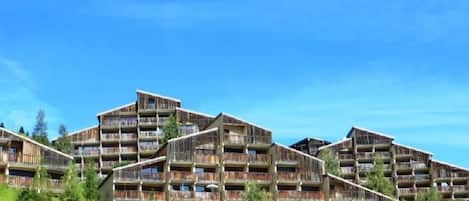 A multi-story hotel with balconies, set against a clear blue sky.