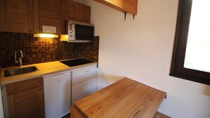 Une cuisine de taille réduite, dotée de meubles en bois, d’un four à micro-ondes, d’un évier et d’un lave-vaisselle.
