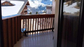 Un balcon donnant sur des montagnes enneigées, avec une balustrade en bois.