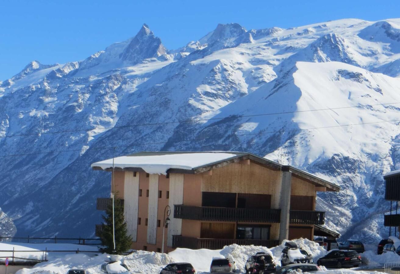 Un refugi de muntanya amb façana de fusta, diversos balcons i un paisatge de muntanya cobert de neu.