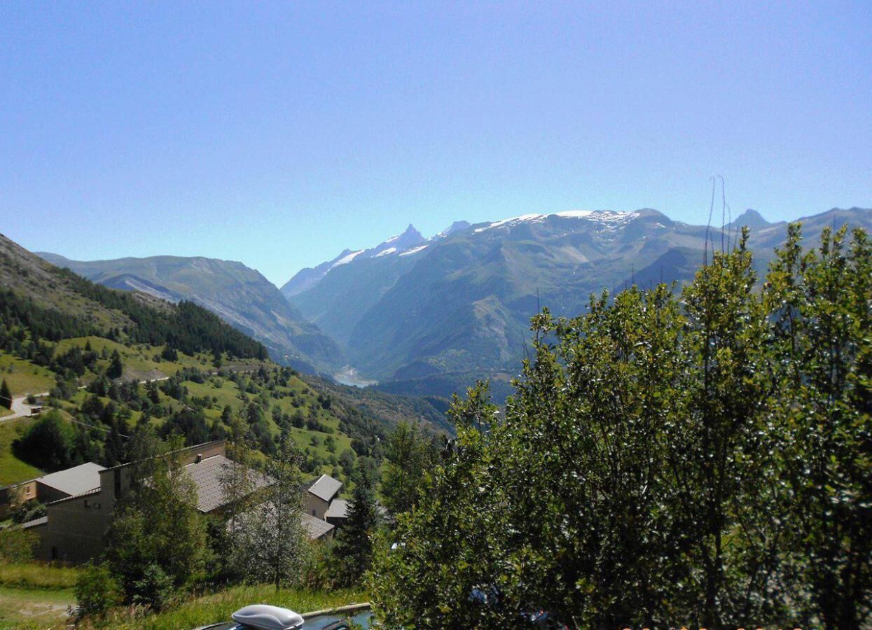 A mountainous landscape with a valley, houses, and a clear sky.