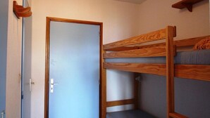 A compact room with a bunk bed, a door, and a small shelf. - 50m from resort center, Ground floor, view mountain, balcony, parking, ski locker, 23m² (Auris)