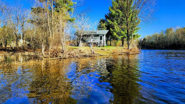 A cabin by a lake surrounded by trees.