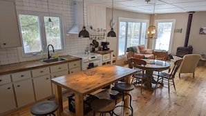 A cozy kitchen with a wooden island, bar stools, and a dining table with chairs.