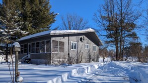 A two-story house with a large front porch and a snow-covered yard.