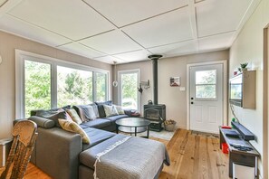 Ein gemütliches Wohnzimmer mit einer Couch, einem runden Couchtisch, einem Kamin und großen Fenstern.