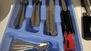 Un porte-ustensiles bleu contenant divers outils de cuisine, notamment des fourchettes, des couteaux et une râpe.