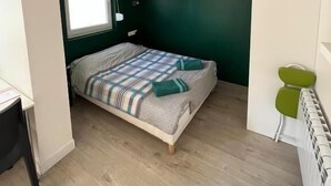 Une petite chambre confortable, avec un lit simple, une fenêtre et un radiateur.