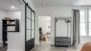 Et moderne soveværelse med seng, garderobe, skrivebord, radiator og et vindue med gardiner.