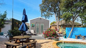 A backyard with a pool, picnic table, and a shed.