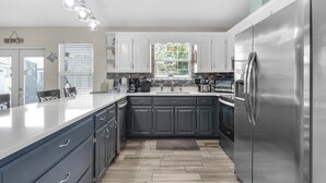A modern kitchen with dark cabinets, a stainless steel refrigerator, and a large island with a light-colored countertop.