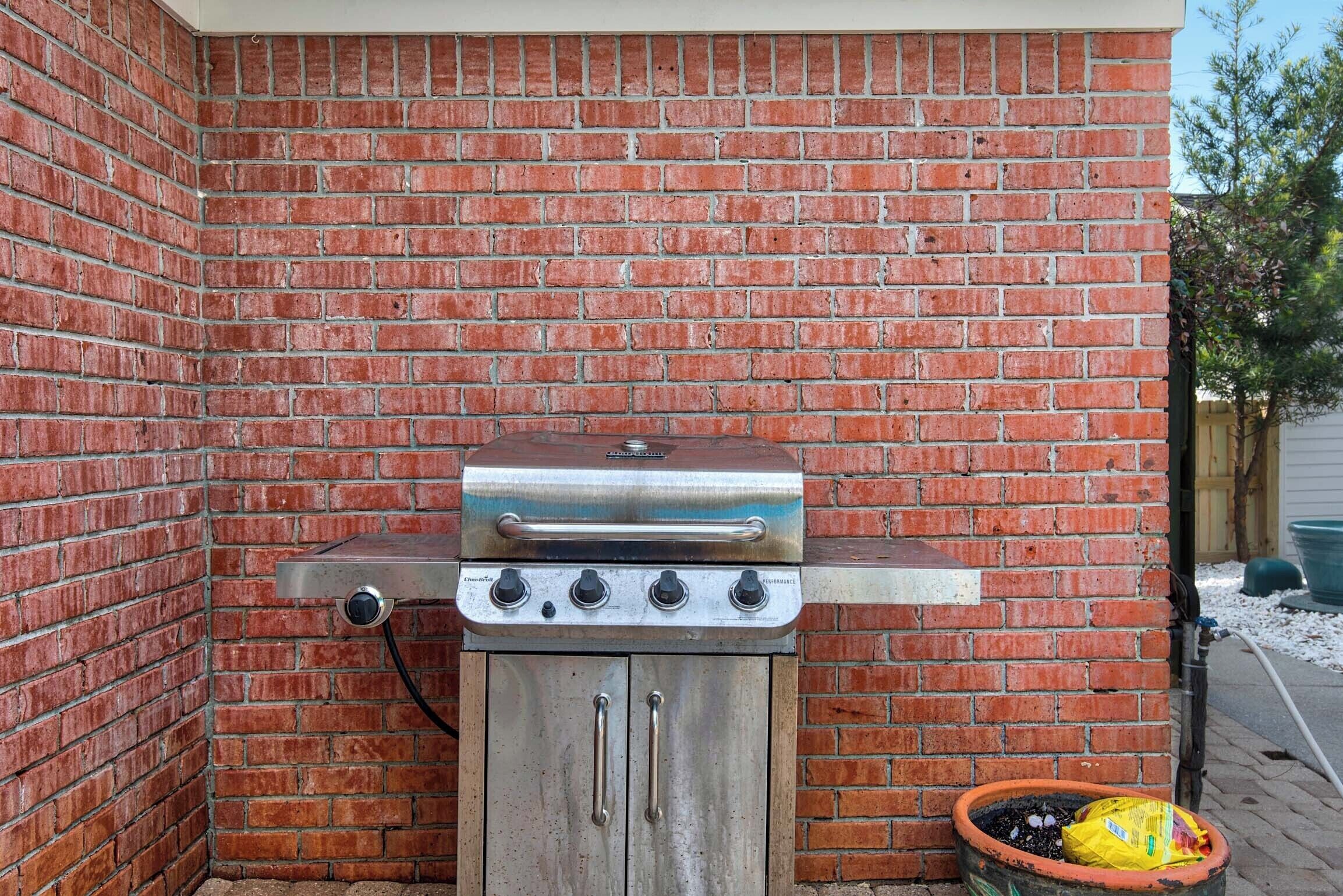 A brick wall with a stainless steel grill attached to it.