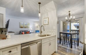 Una cucina moderna con una grande isola, elettrodomestici in acciaio inossidabile e luci a sospensione.