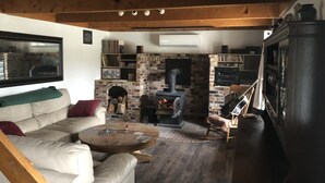 A cozy living room with a brick fireplace, a sofa, a coffee table, and a bookshelf.