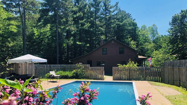 A backyard with a swimming pool, a wooden house, and a wooden fence.