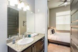 A modern bathroom with a granite countertop, a white sink, and a large mirror.