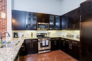 Enjoy cooking in this well-equipped kitchen with a granite countertop, stainless steel sink, and range hood.