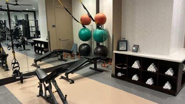 A gym with exercise equipment, a mirror, and shelves with white objects.
