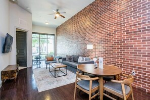 A modern living room with a brick wall, a sofa, a coffee table, and a dining table with chairs.