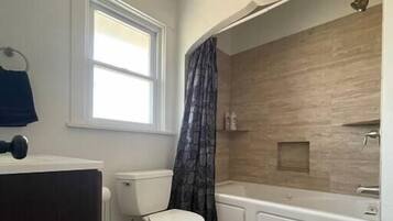 Une salle de bain avec des toilettes, une baignoire et une fenêtre.