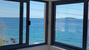 A room with large windows overlooking a body of water, with a clear view of the sea and a distant landmass. - Apartments Blaža (Prvic Luka)