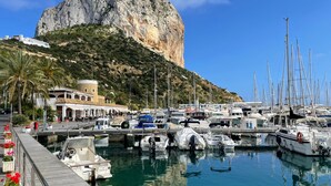 A marina with boats docked, a large rock formation in the background, and a building with a tiled roof. - High Quality Villa, 39 Five STAR REVIEWS, Beach 5 min drive, Heated Pool. (Calpe)