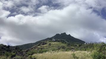 Una montaña con un primer plano cubierto de hierba y un cielo nublado.