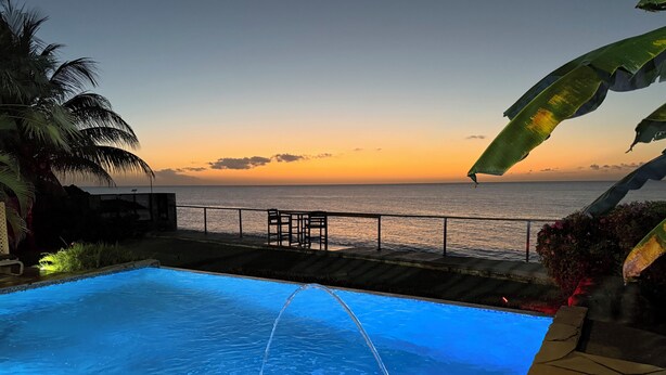Une piscine avec vue sur l’océan au coucher du soleil.