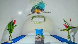 Ein Zimmer mit einem Bett, einem kleinen Tisch mit Handtüchern und zwei Vasen mit Pflanzen.