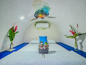 Una habitación con una cama, una mesita con toallas y dos jarrones con plantas.