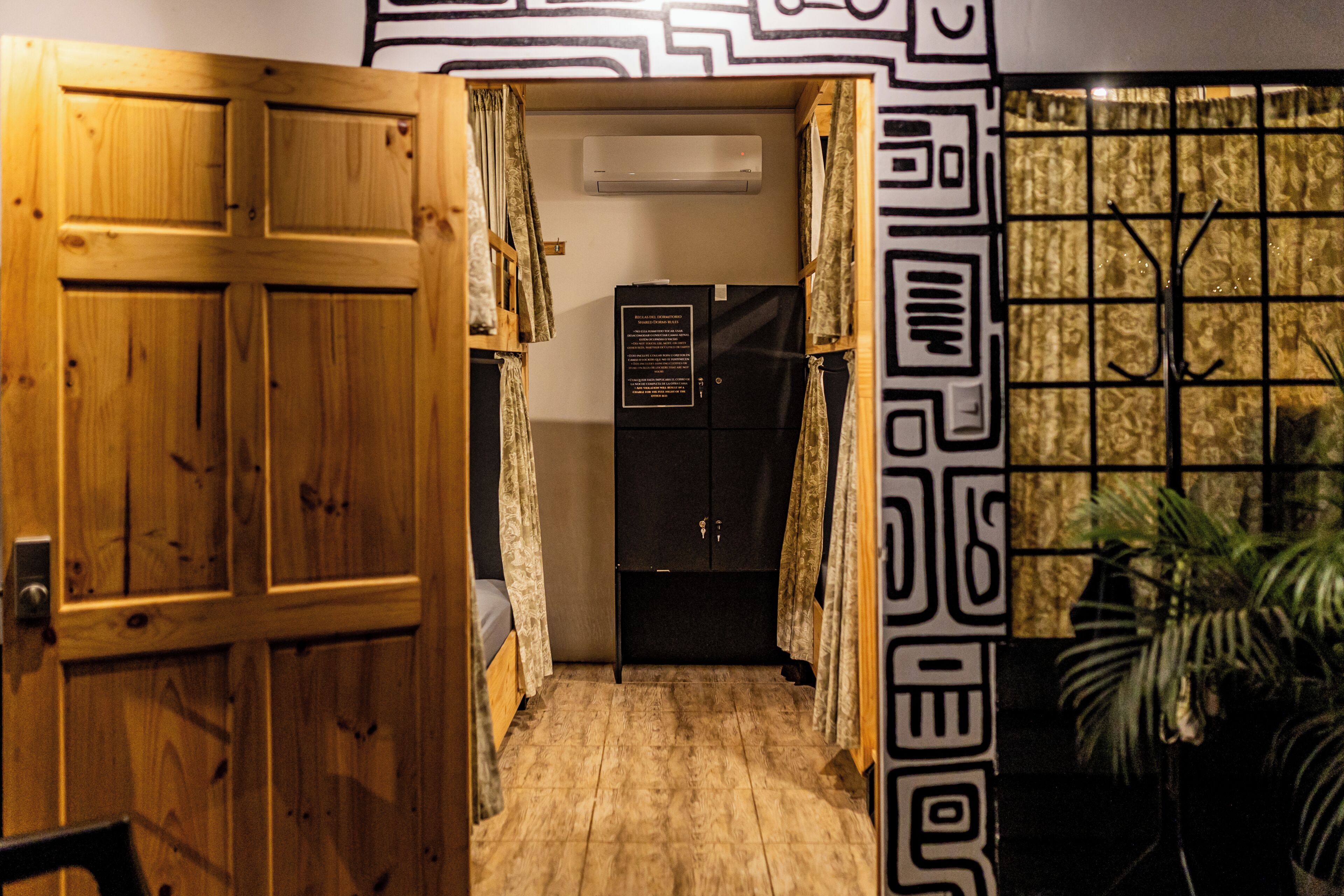 A narrow hallway with a wooden door, a black cabinet, and a patterned wall.