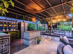 An outdoor bar area with a counter, seating, and potted plants. - Koru Boutique Hostel (Uvita)