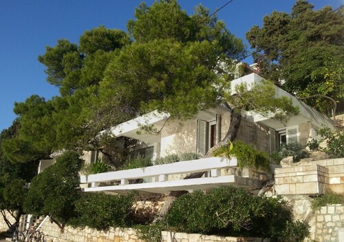 Maison d'architecte avec grandes terrasses ombragées en front de mer.