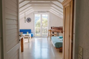 Una habitación con cama, escritorio, piano y vistas a través de un ventanal.
