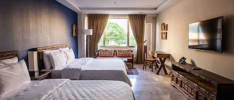 Habitación de hotel con dos camas, televisión, escritorio y ventana con cortinas.