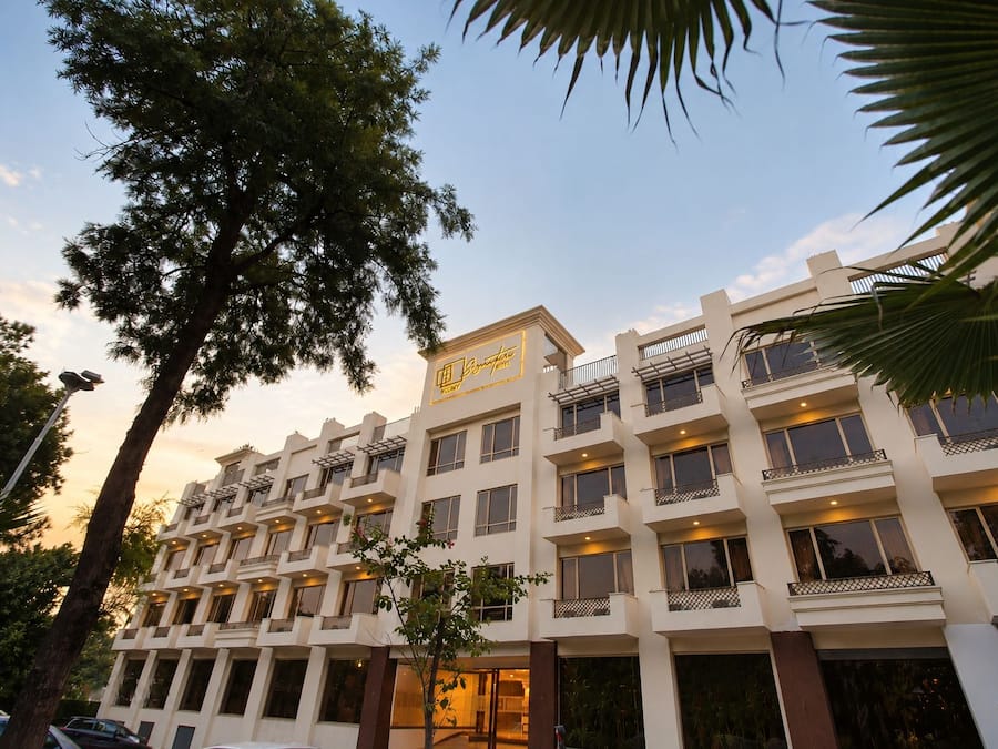 Un hotel de varios pisos con balcones, una señal que indica que es un hotel, y un cielo despejado.