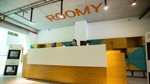 A reception desk with a sign above it that reads "ROOMY". - Roomy Signature Hotel (Islamabad)