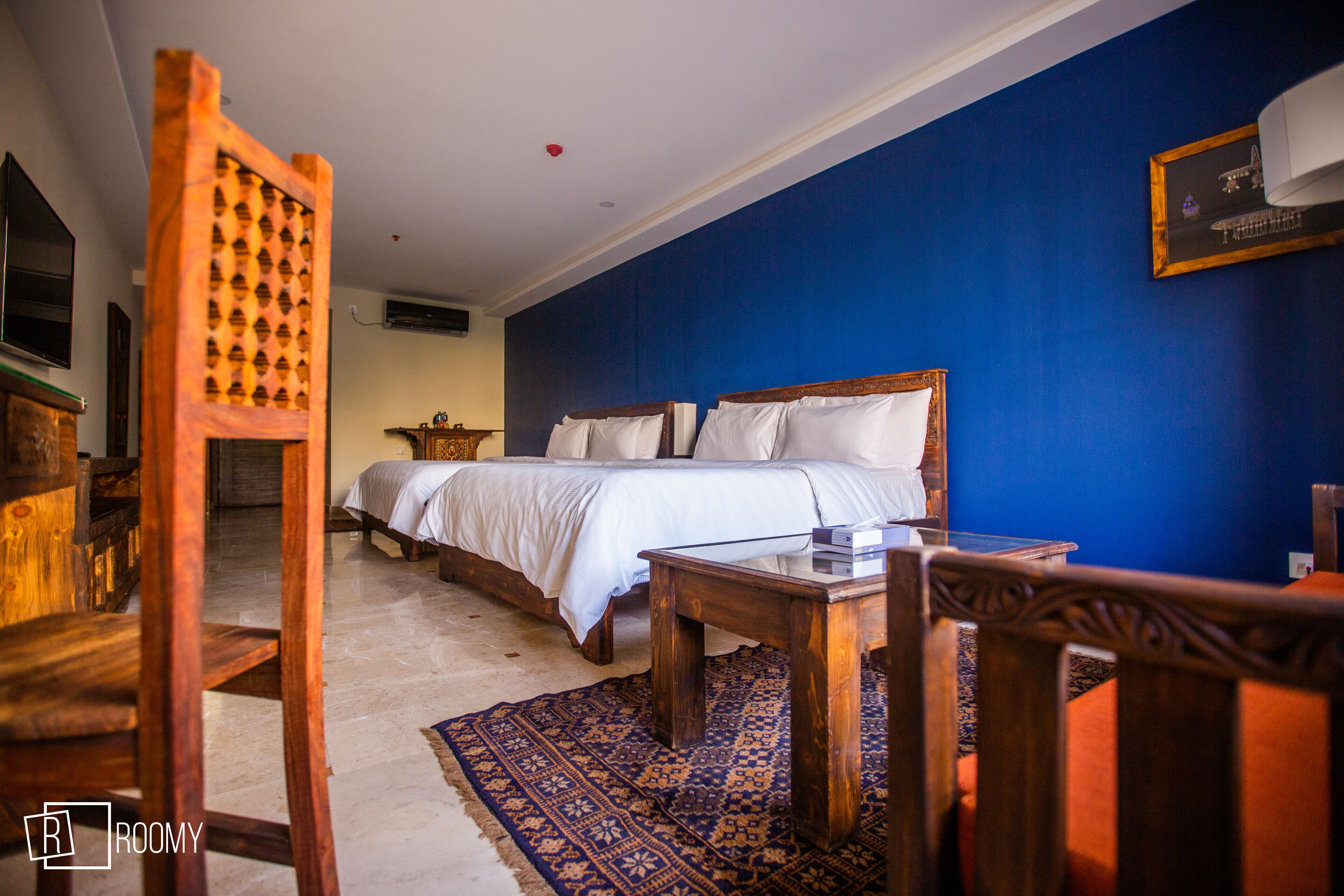 A bedroom with a large bed, wooden furniture, and a blue accent wall.