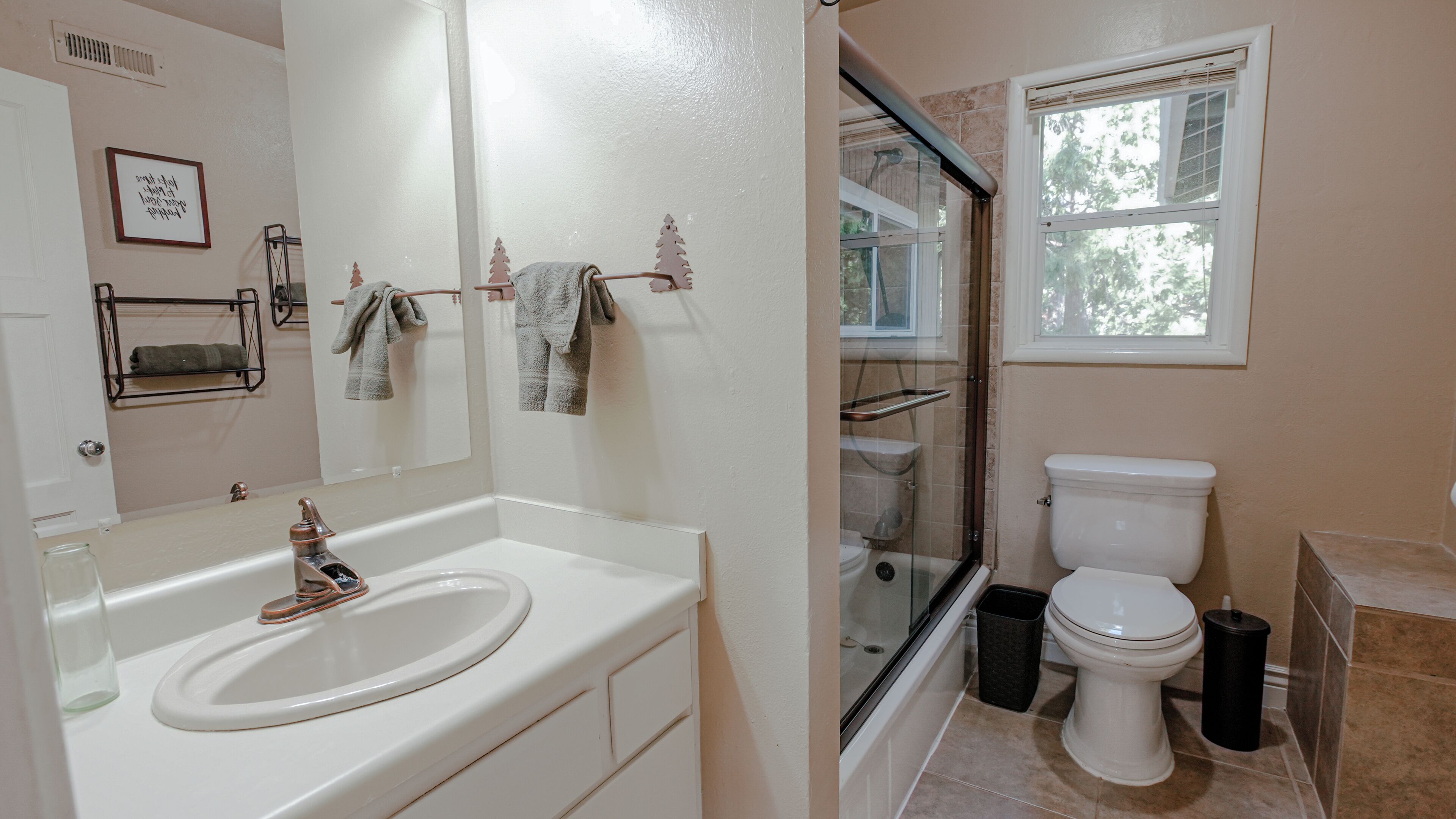 Une salle de bain avec un lavabo blanc, une cabine de douche en verre, des toilettes et une fenêtre.