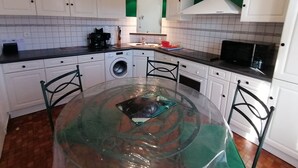 Une cuisine compacte avec des meubles blancs, un lave-linge, un four à micro-ondes et une table à manger avec des chaises.