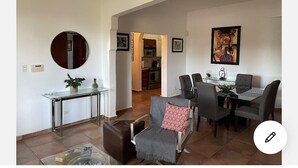 A modern living room with a glass coffee table, a leather ottoman, and a dining area with a glass table and chairs. - NEW&GORGEOUS Great View nearCondado beach 5B 2B 1 parking (San Juan)