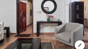 A living room with a grey sofa, a wooden coffee table, a round mirror, and a small console table with a vase of flowers. - NEW&GORGEOUS Great View nearCondado beach 5B 2B 1 parking (San Juan)